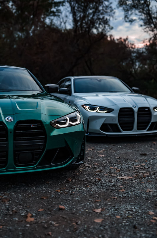 Two BMW M3 performance cars parked outdoors at dusk